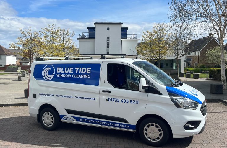 Blue Tide Window Cleaning van parked in a residential area, featuring blue branding, company logo, phone number, and website on the side