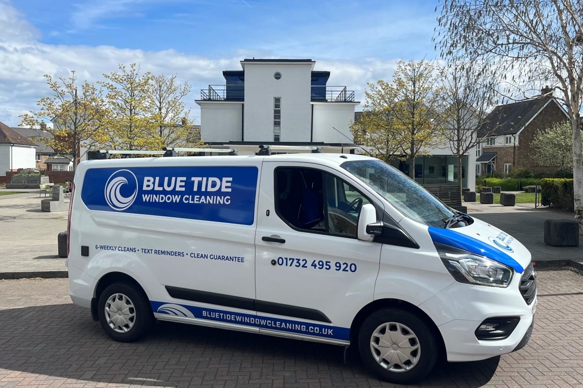 Blue Tide Window Cleaning van parked in a residential area, featuring blue branding, company logo, phone number, and website on the side